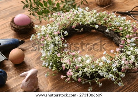 Composition with Easter wreath, flowers and eggs on wooden background, closeup
