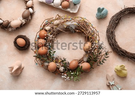 Composition with Easter wreath, flowers, feathers and eggs on beige grunge background