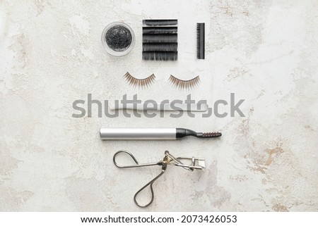 Composition with false eyelashes and tools on light background