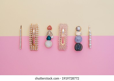Composition of fashion accessories and hair clips for a hairstyle stylist on a pastel yellow and pink background