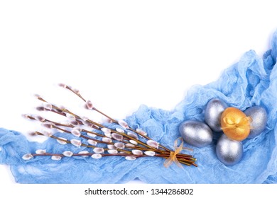 Composition of five golden and silver colored Easter eggs decorated with bow and spring willow catkins bouquet on light blue gauze fabric isolated on white background. Copy space. Easter background. 