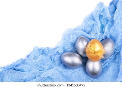 Composition of five silver and golden colored Easter eggs decorated with bow on light blue gauze fabric isolated on white background 