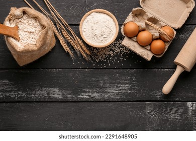 Composition with flour, wheat ears, eggs and rolling pin on black wooden table - Powered by Shutterstock