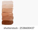 Composition of foundation cream smears in various shades on a light background. Makeup product, smooth and blendable textures.