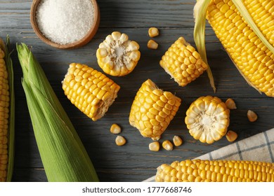 Composition with fresh raw corn and cutting board on wooden table