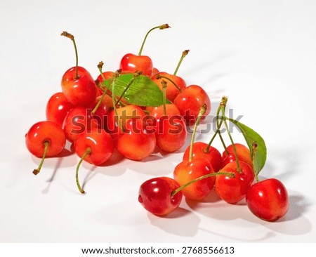 Composition of fresh raw white cherries shot on whte reflective surface.
