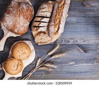 Composition of freshly baked bread on chopping boards and wheat ears on dark wooden background. Bakery and healthy eating. Flat lay. Top view - Powered by Shutterstock