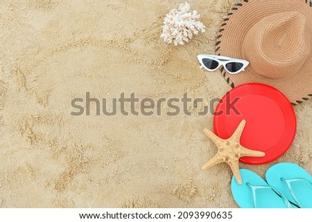 Composition with frisbee disk and beach accessories on sand