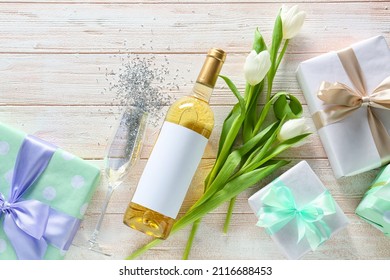 Composition With Gift Boxes, Flowers And Bottle Of Wine For International Women's Day Celebration On Light Wooden Background