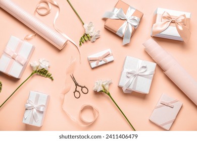 Composition with gift boxes, wrapping paper and freesia flowers on nude background
