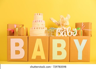 Composition with gifts and cake for baby shower party against color background