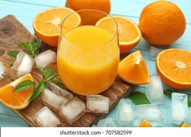 Composición con vaso de zumo fresco y naranjas sobre fondo de madera color