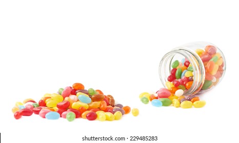 Composition Of A Glass Jar And Multiple Colorful Jelly Bean Candies, Isolated Over The White Background