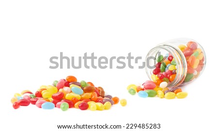 Composition of a glass jar and multiple colorful jelly bean candies, isolated over the white background