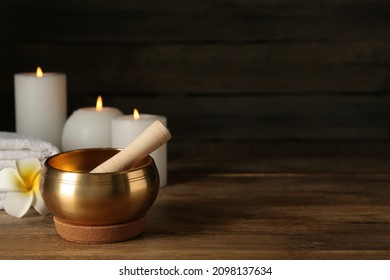 Composition with golden singing bowl on wooden table, space for text
