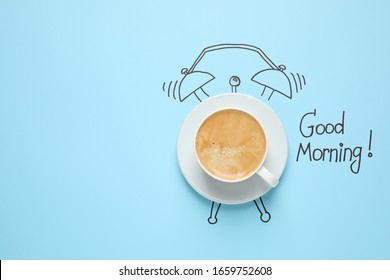 Composition with Good Morning wish and aromatic coffee on light blue background, top view. Space for text