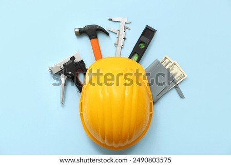 Composition with hardhat, construction tools and money on color background