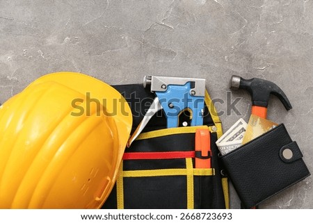 Composition with hardhat, construction tools, wallet and money on grunge background, closeup