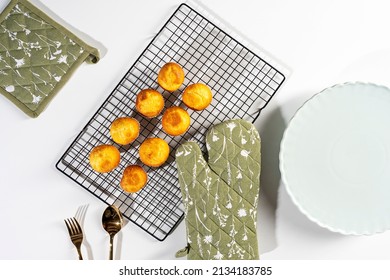 Composition of homemade Baked Cupcakes, oven mitt, golden cutlery and an empty saucer, white background, top view - Shutterstock ID 2134183785