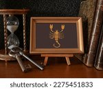 Composition of hourglasses, keys, old books of the zodiac sign in a frame on a stand