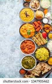 Composition of Indian cuisine in ceramic bowls on stone table. Tikka masala, butter chicken, Nilgiri, seekh kebab, rice, Onion Bhajia, paneer, samosa, naan, Daal Tarka, spices With copy space