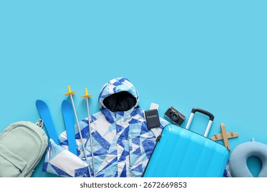 Composition with jacket, suitcase and accessories on blue background