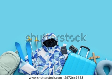 Composition with jacket, suitcase and accessories on blue background