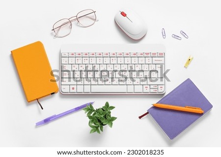 Composition with keyboard, mouse, glasses and notebook on white background