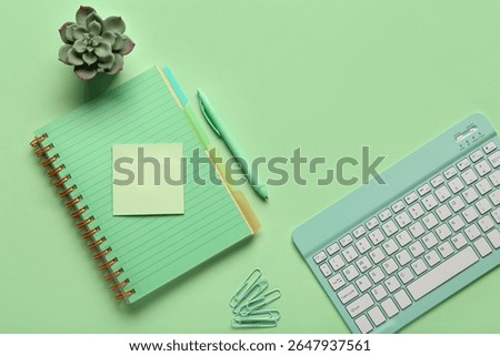 Composition with keyboard, notebook and paper clips on green background.Top view