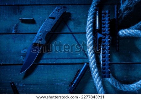Composition with a knife and a flashlight. Pocket knife and flashlight. Cold light. Sleeves and a knife. View from above.