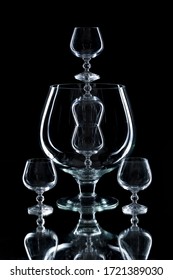 Composition of large and small glasses and wine glasses. The glass material. Black background. Mirror. Subject shooting in a photo Studio.
