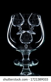 Composition of large and small glasses and wine glasses. The glass material. Black background. Mirror. Subject shooting in a photo Studio.