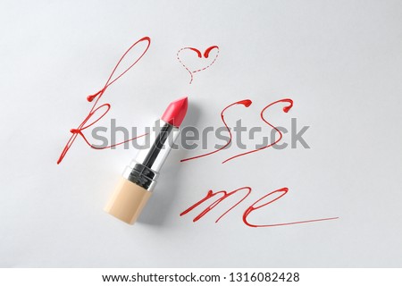 Composition with lipstick and text KISS ME on light background