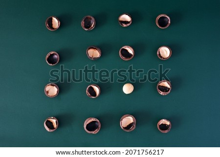 Composition of Macadamia nutshell with one cracked open stands out 