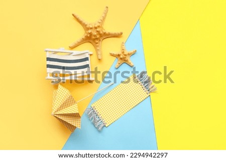 Composition with miniature deck chair, starfishes and paper umbrella on colorful background