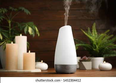 Composition with modern aroma humidifier on wooden table against brown background, space for text