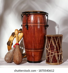 Composition Of Musical Ethnic Instrument. Maracas, Tambourine, Conga And Ethnic Drum. Percussion Rhytm Instruments Are On White Background With Palm Shade. Cuban Sound, Latin Culture, Samba And Rumba