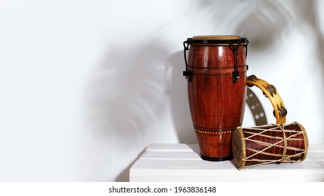 Composition of musical ethnic instrument. Maracas, tambourine, conga and ethnic drum. Percussion rhytm instruments are on white background with palm shade. Cuban sound, latin culture, samba and rumba