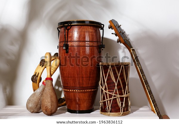 Composition\
of musical ethnic instrument. Maracas, tambourine, conga, guitar\
and ethnic drum. Percussion rhytm instruments under palm shade.\
Cuban sound, latin culture, samba and\
rumba