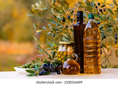 Composition of olive tree branch, bottles with olive oil and preserved olives in jar on table outdoors. - Powered by Shutterstock