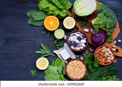 Composition On A Dark Background Of Products Containing Folic Acid, Vitamin B9 - Green Leafy Vegetables, Citrus, Beans, Peas, Nuts, Yeast. Top View. Flat Lay. Healthy Food