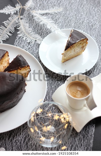 composition on the table.  cake covered with
chocolate icing.  a slice of cake on a white plate.  a cup of
coffee in a white
service.