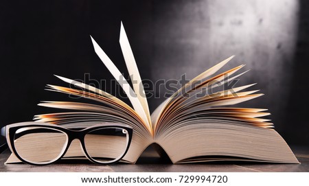 Composition with open book and glasses on the table.