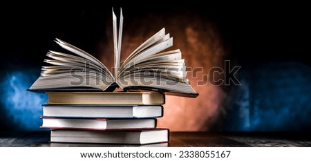 A composition with an open book lying on a stack of other books 