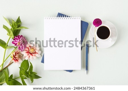 Composition with opened blank notepad, cup of black coffee, flowers dahlias on gray background. Festive office desktop concept. Morning coffee cup.