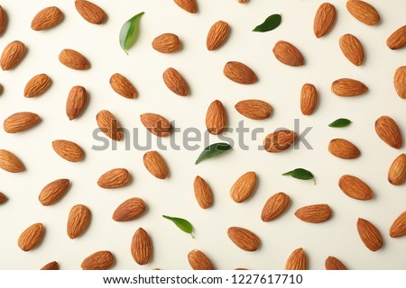 Composition with organic almond nuts on light background, top view