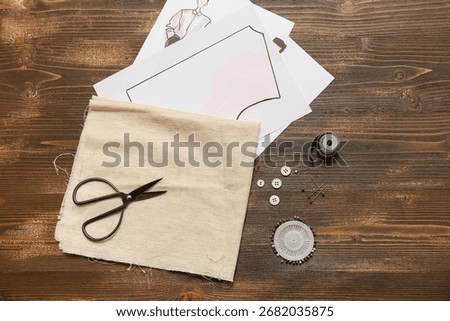 Composition with pattern and sewing accessories on wooden brown background. Top view