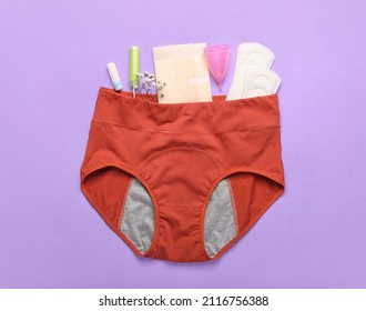 Composition with period panties, pads, tampons and menstrual cup on lilac background