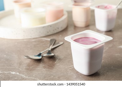 Composition with plastic cups with yogurt on grey table, space for text