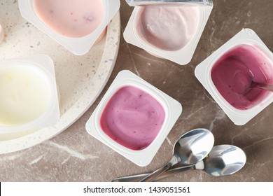 Composition with plastic cups with yogurt on grey table